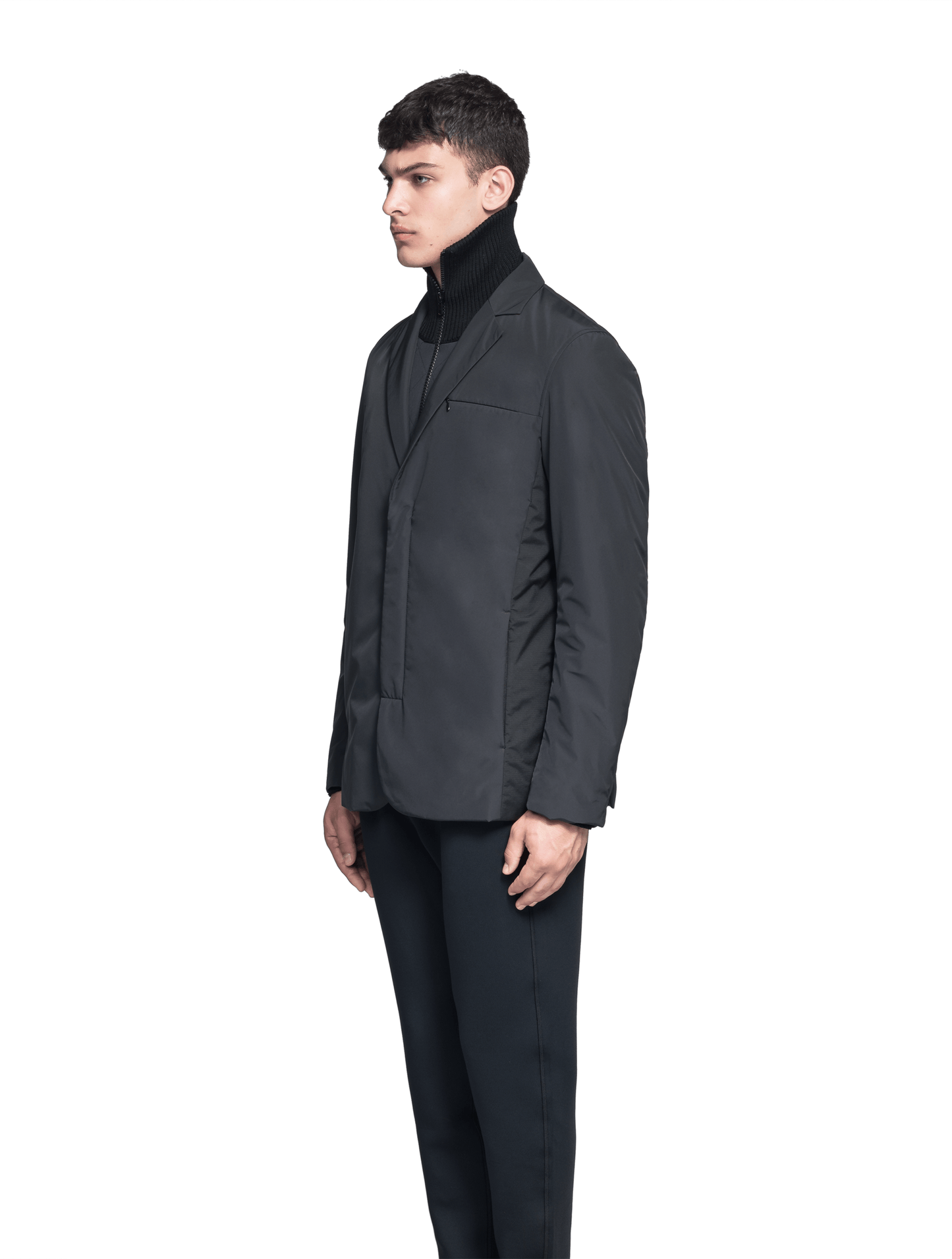 Cody Men's Tailored Travel Blazer in 3-ply micro denier and stretch nylon fabrication with DWR coating, Primaloft Gold Insulation Active+, hidden two-way zipper at centre front with snap closure placket, three invisible exterior zipper pockets, double back pleats, and hidden snap placket at cuffs, in Black