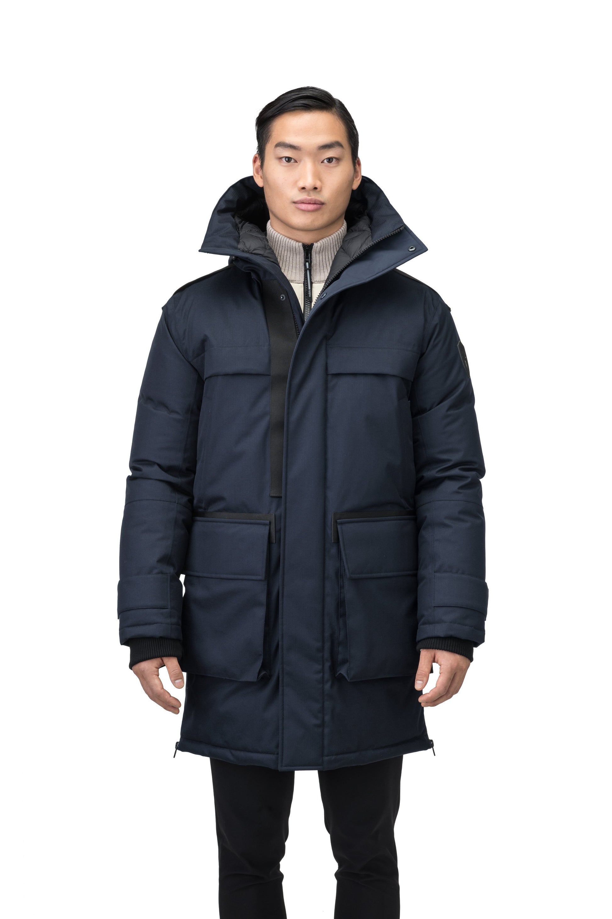 Alum Men's Long Parka in thigh length, Premium Canadian White Duck Down insulation, non-removable hood with removable coyote fur trim, two-way centre front zipper with magnetic closure wind flap, four exterior patch pockets at front, in Navy