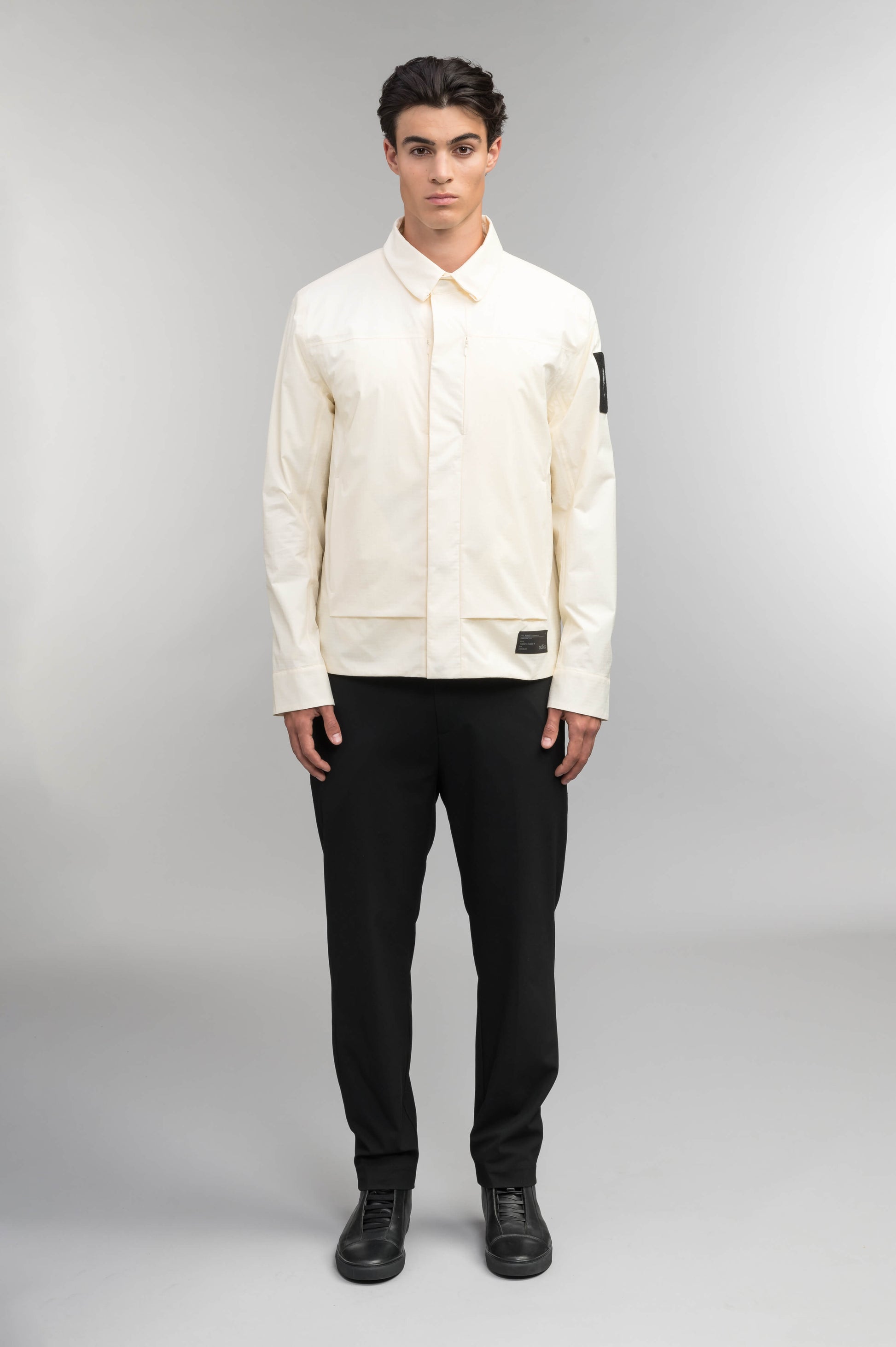 Farson Men's Waterproof Overshirt in Wheat made from premium recycled polyester ripstop with a DWR coating. Features a concealed snap-button front placket, adjustable snap cuffs, invisible chest zip pocket, dual zippered waist pockets, pit zip ventilation, and seam-sealed construction for enhanced weather protection. Designed in Canada.