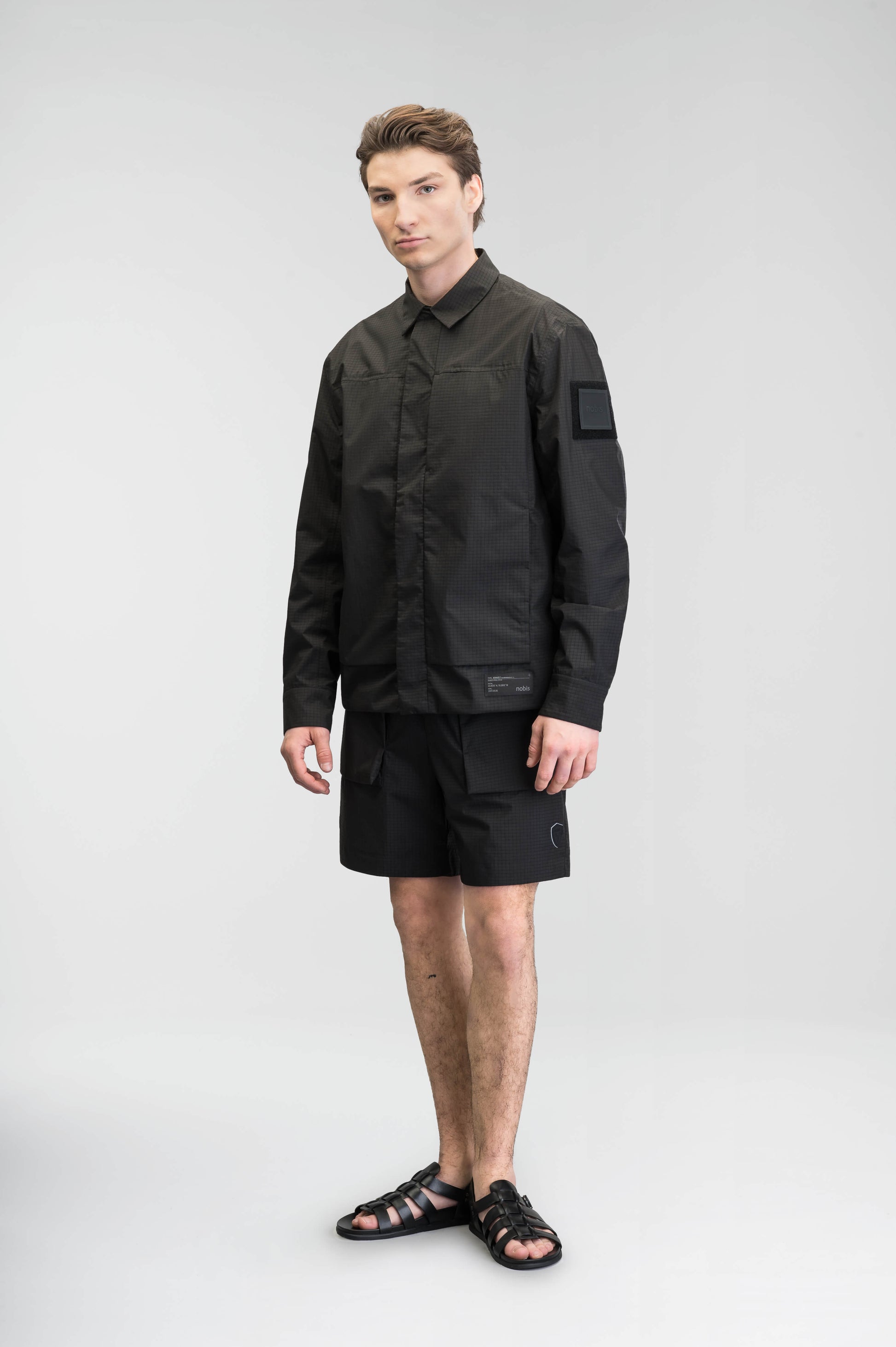 Farson Men's Waterproof Overshirt in Black made from premium recycled polyester ripstop with a DWR coating. Features a concealed snap-button front placket, adjustable snap cuffs, invisible chest zip pocket, dual zippered waist pockets, pit zip ventilation, and seam-sealed construction for enhanced weather protection. Designed in Canada.