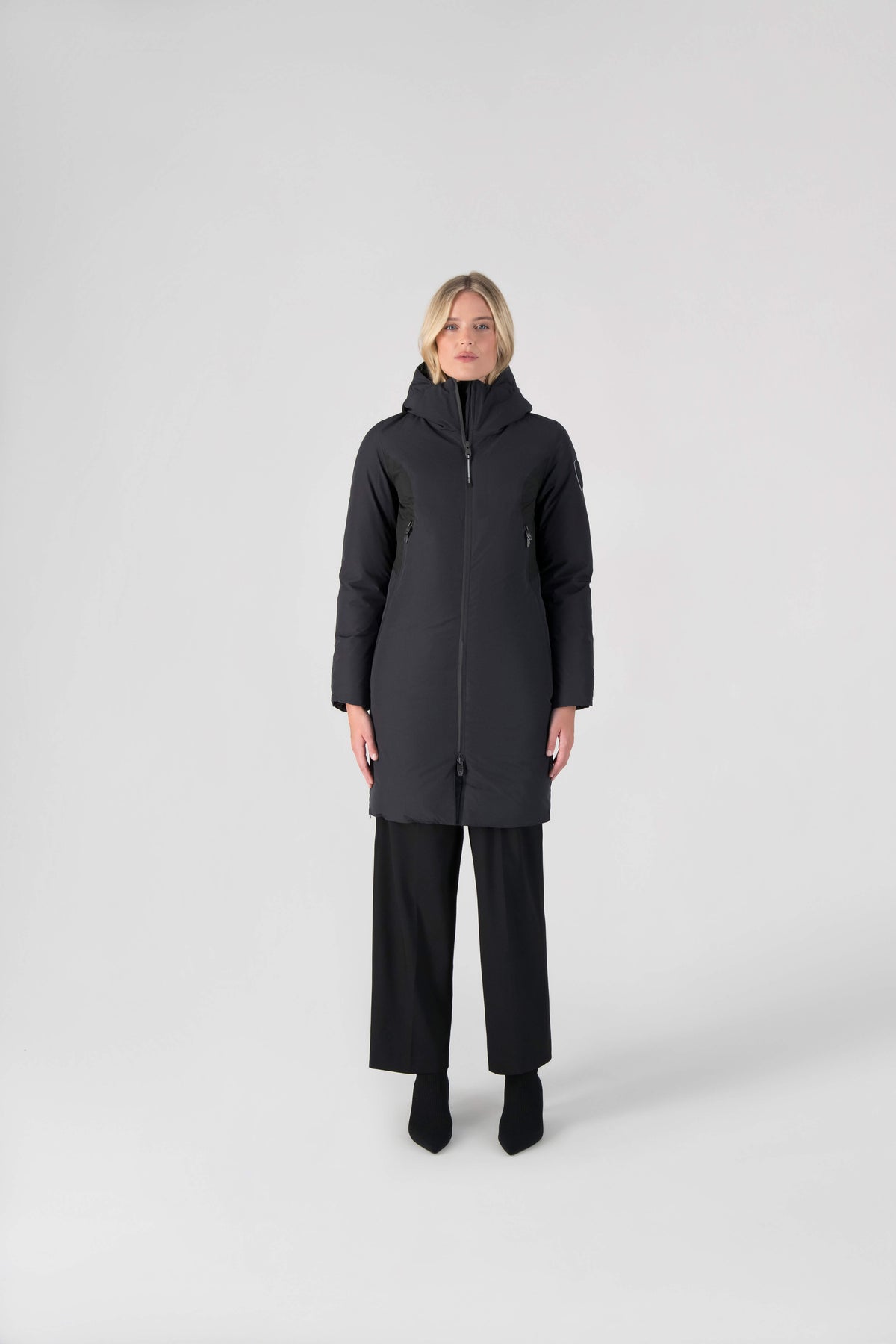 Inara Women's Performance Parka in knee length, premium 3-ply micro denier and stretch ripstop fabrication with DWR coating, Premium Canadian White Duck Down insulation, non-removable down-filled hood, centre front two-way zipper, large vertical zipper pockets along waist, zipper vents along bottom side hem, in Black