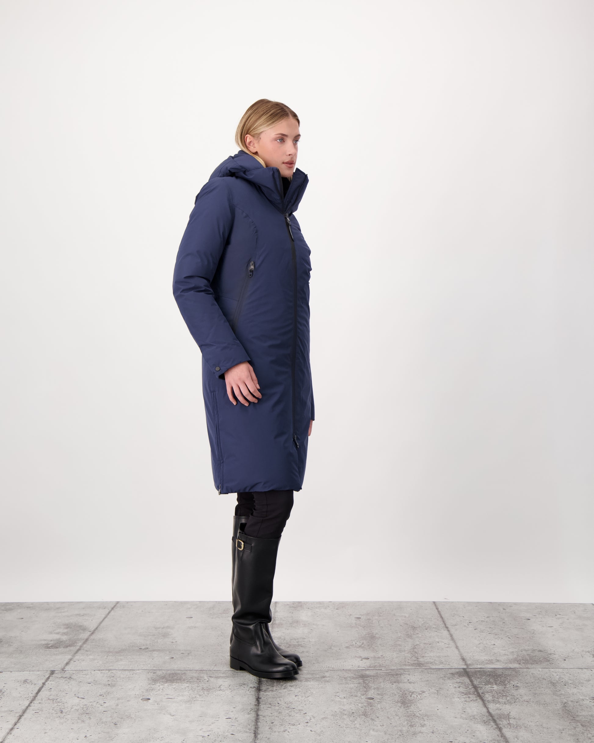 Inara Women's Performance Parka in knee length, premium 3-ply micro denier and stretch ripstop fabrication with DWR coating, Premium Canadian White Duck Down insulation, non-removable down-filled hood, centre front two-way zipper, large vertical zipper pockets along waist, zipper vents along bottom side hem, in Marine