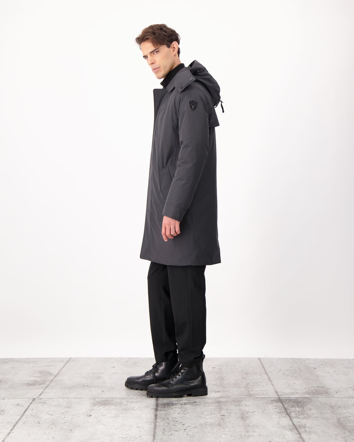 Nord Men's Tailored Trench Coat in knee length, 3-Ply Micro Denier and 4-Way Durable Stretch Weave fabrication, Premium Canadian White Duck Down insulation, removable down-filled hood, exterior zipper pocket at left chest, and adjustable snap button cuffs, in Black