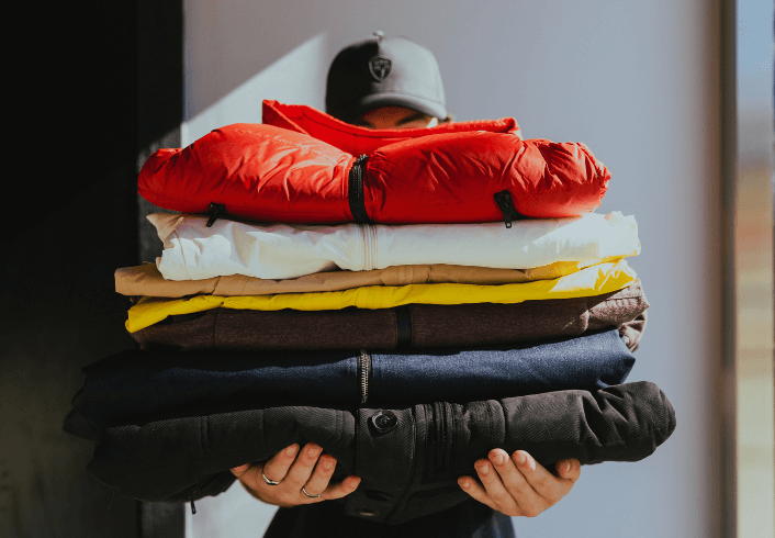Stack of Nobis Outerwear being held in front of a person