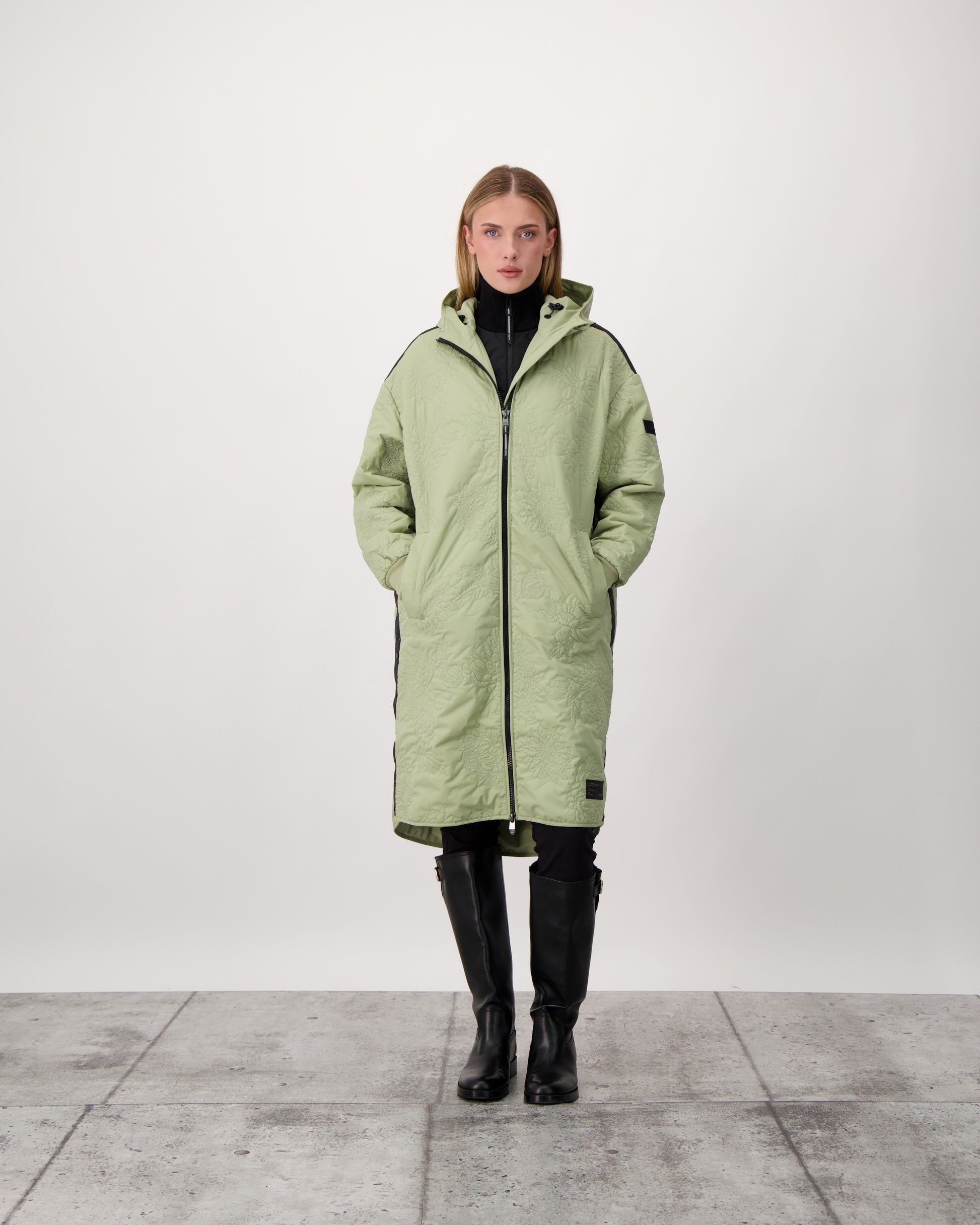 Surrey Women's Performance Quilted Long Mid Layer Jacket in knee length, Primaloft Gold Insulation Active+, non-removable hood, single welt magnetic closure pockets, ribbed cuffs, two-way centre front zipper, grosgrain ribbon detail and shoulders and side seam, and snap closure side seam vents, in Tea
