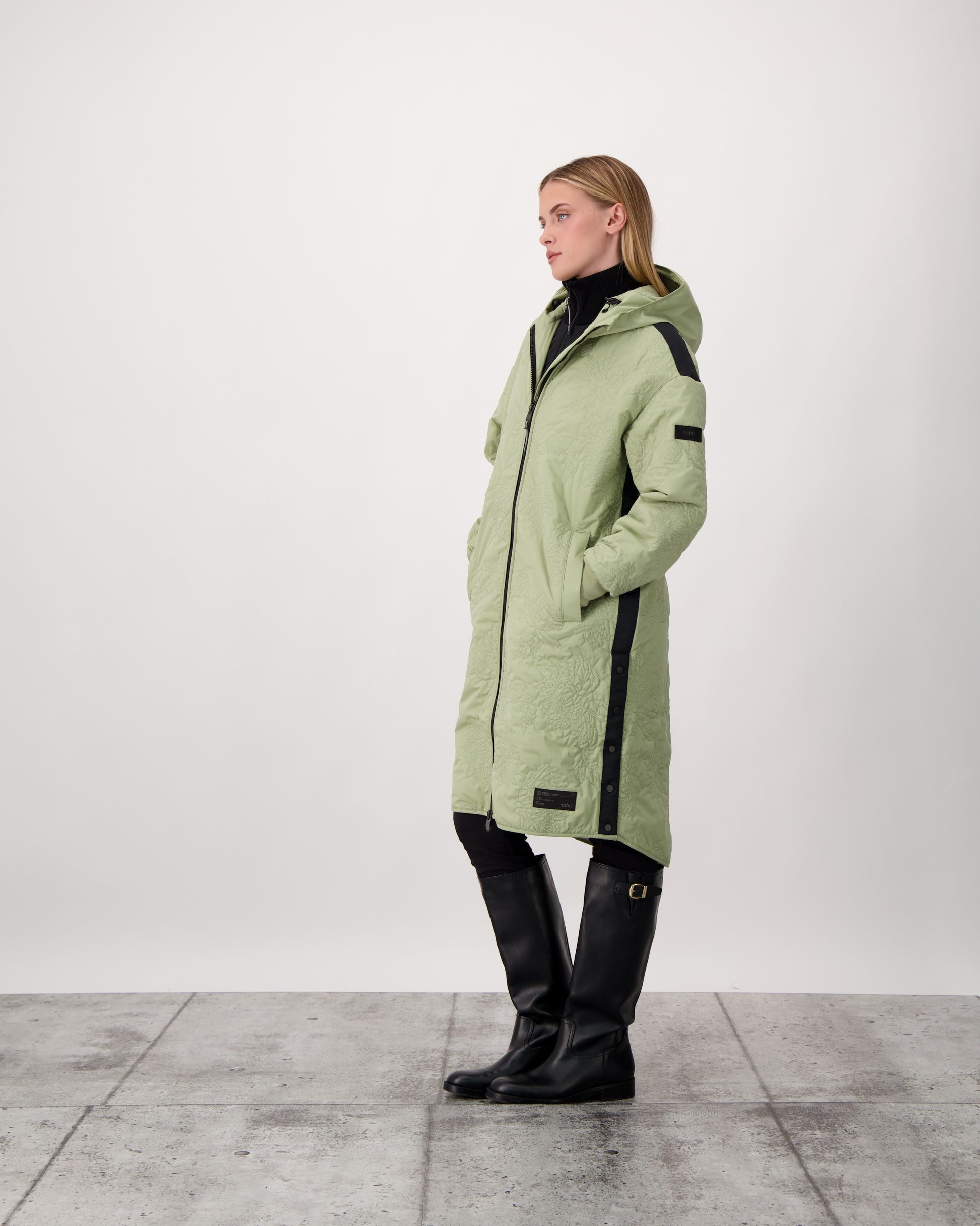 Surrey Women's Performance Quilted Long Mid Layer Jacket in knee length, Primaloft Gold Insulation Active+, non-removable hood, single welt magnetic closure pockets, ribbed cuffs, two-way centre front zipper, grosgrain ribbon detail and shoulders and side seam, and snap closure side seam vents, in Tea