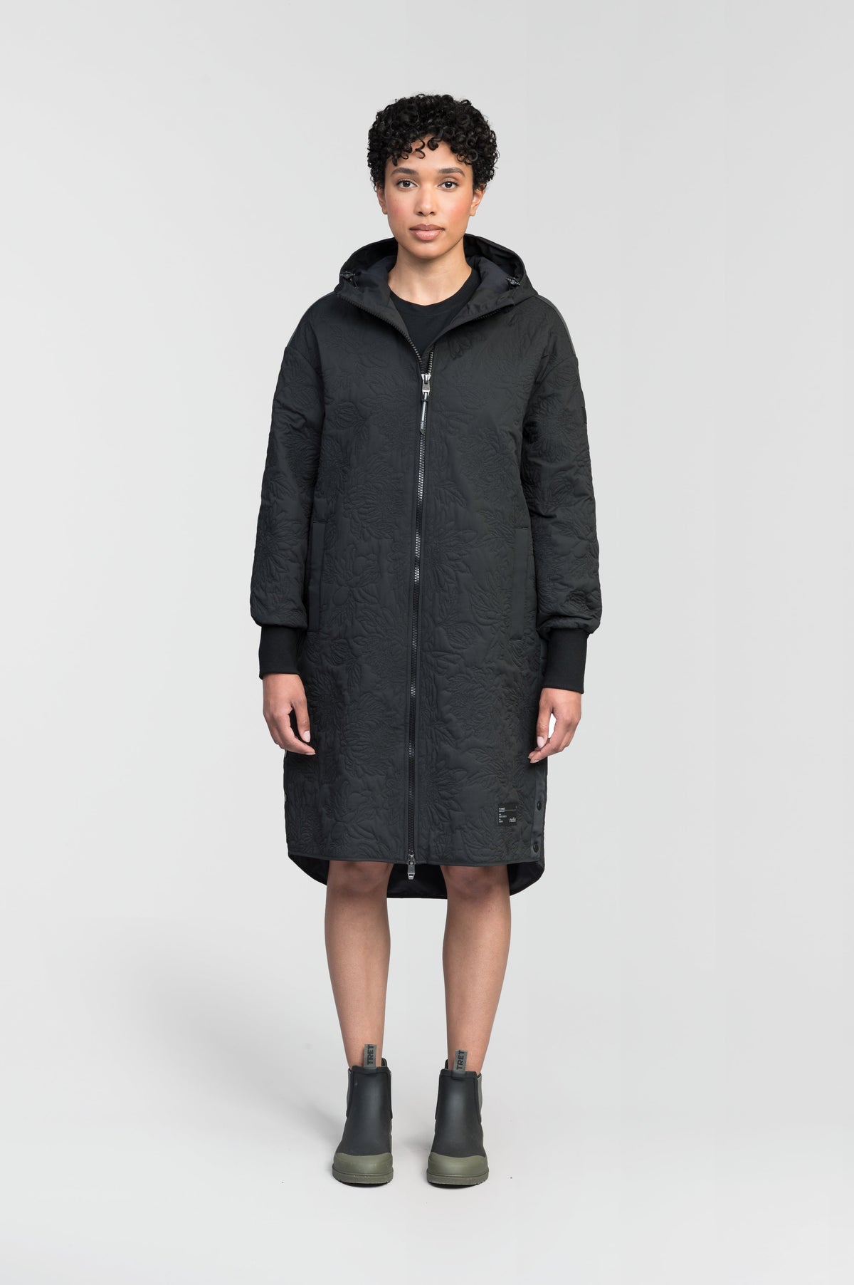 Surrey Women's Performance Quilted Long Mid Layer Jacket in knee length, Primaloft Gold Insulation Active+, non-removable hood, single welt magnetic closure pockets, ribbed cuffs, two-way centre front zipper, grosgrain ribbon detail and shoulders and side seam, and snap closure side seam vents, in Black