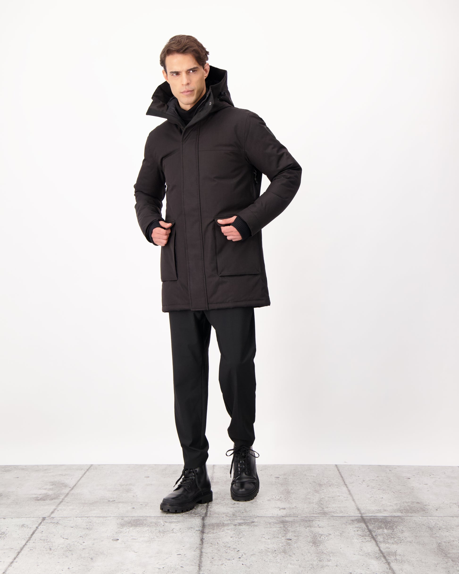 Yves Furless Men's Parka in thigh length, Canadian white duck down insulation, non-removable down-filled hood, flap pockets at waist, centre-front two-way zipper with magnetic wind flap, and elastic ribbed cuffs, in CH Black