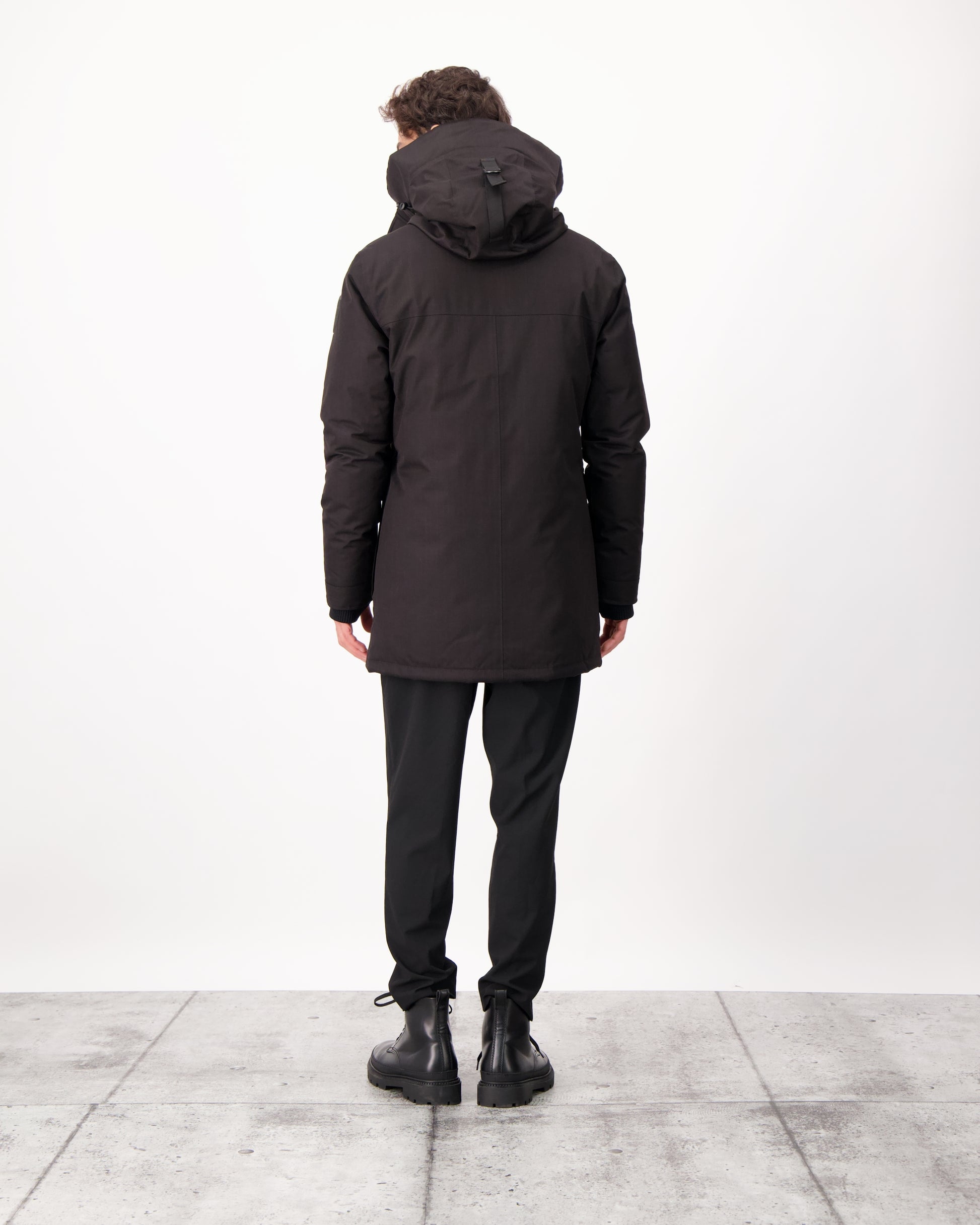 Yves Furless Men's Parka in thigh length, Canadian white duck down insulation, non-removable down-filled hood, flap pockets at waist, centre-front two-way zipper with magnetic wind flap, and elastic ribbed cuffs, in CH Black