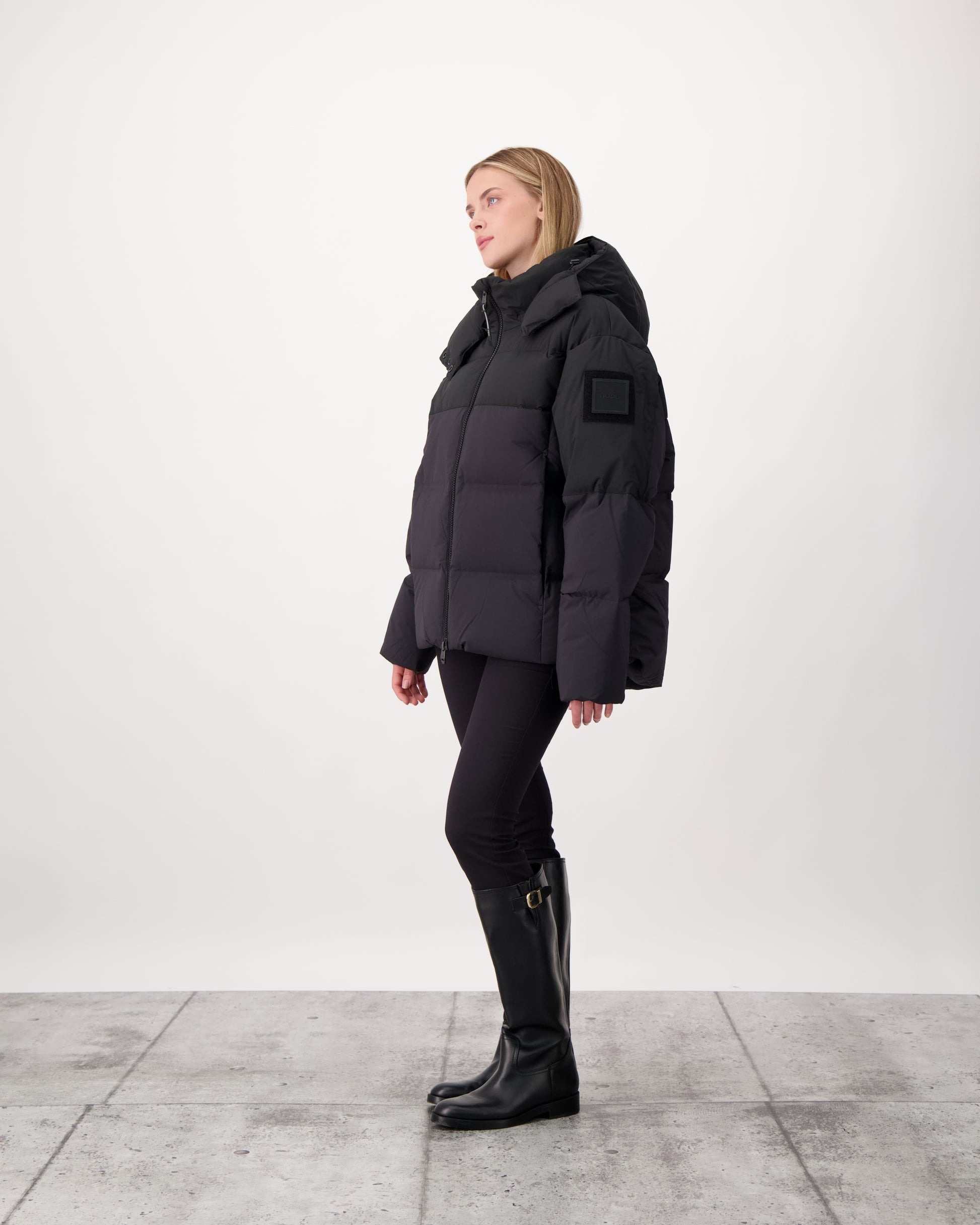 Una Ladies Performance Puffer in hip length, Technical Taffeta and Durable Stretch Ripstop fabrication, Premium Canadian White Duck Down insulation, removable down filled hood, centre front two-way zipper, and side-entry pockets at waist, in Black