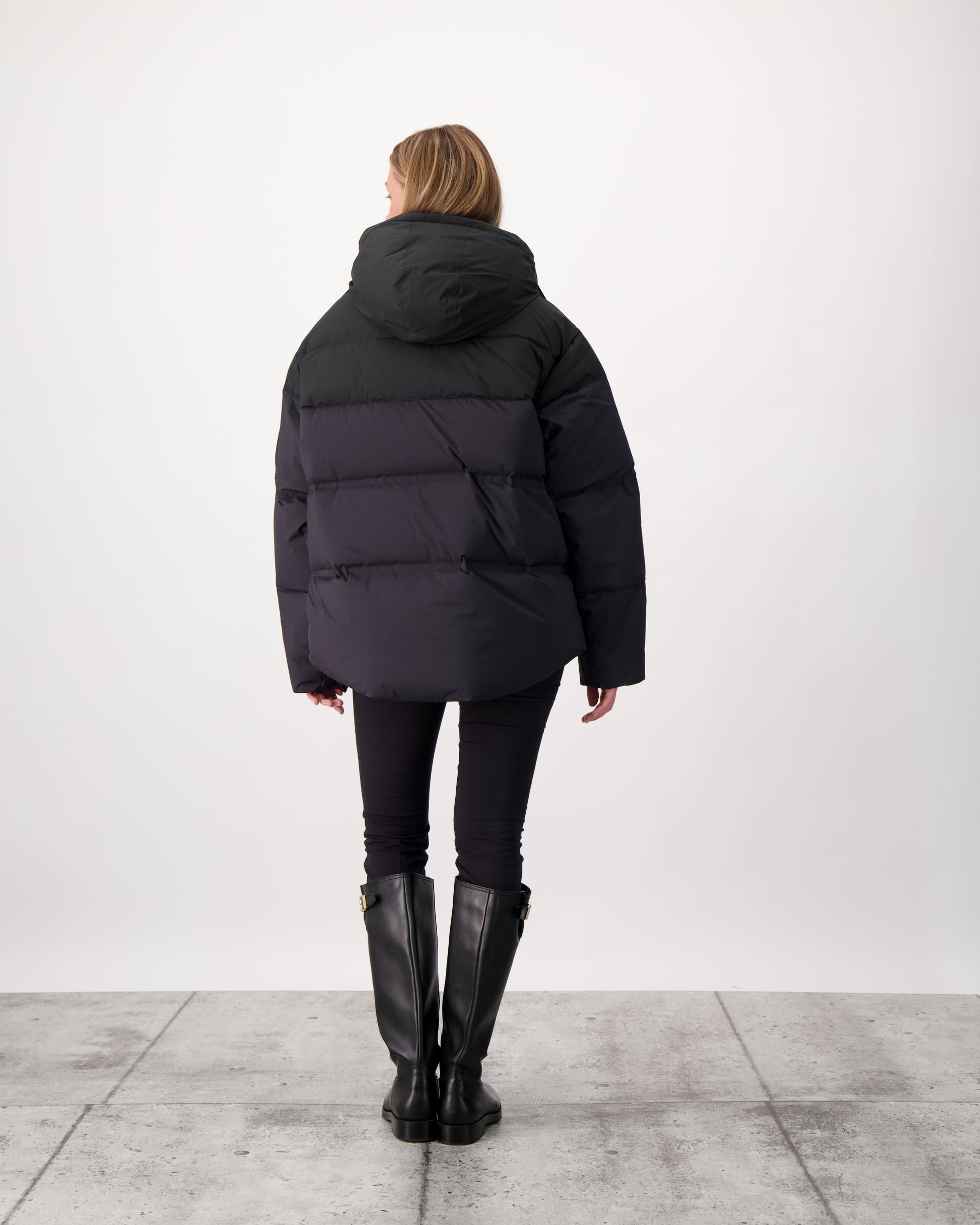 Una Ladies Performance Puffer in hip length, Technical Taffeta and Durable Stretch Ripstop fabrication, Premium Canadian White Duck Down insulation, removable down filled hood, centre front two-way zipper, and side-entry pockets at waist, in Black