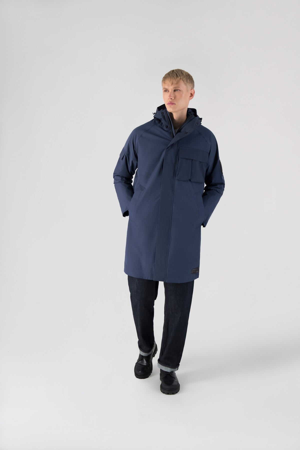 Wylder Men's Performance Rain Jacket in knee length, premium 3-ply Micro Denier and stretch ripstop fabrication, non-removable hood with reflective piping and adjustable draw cord, split utility chest pocket with magnetic flap closure, single welt pockets with magnetic closure at waist, back yoke with mesh ventilation, snap button wind flap, two-way branded zipper at centre front, telescopic sleeves with elasticized cuffs, interior draw cord at waist, in Marine
