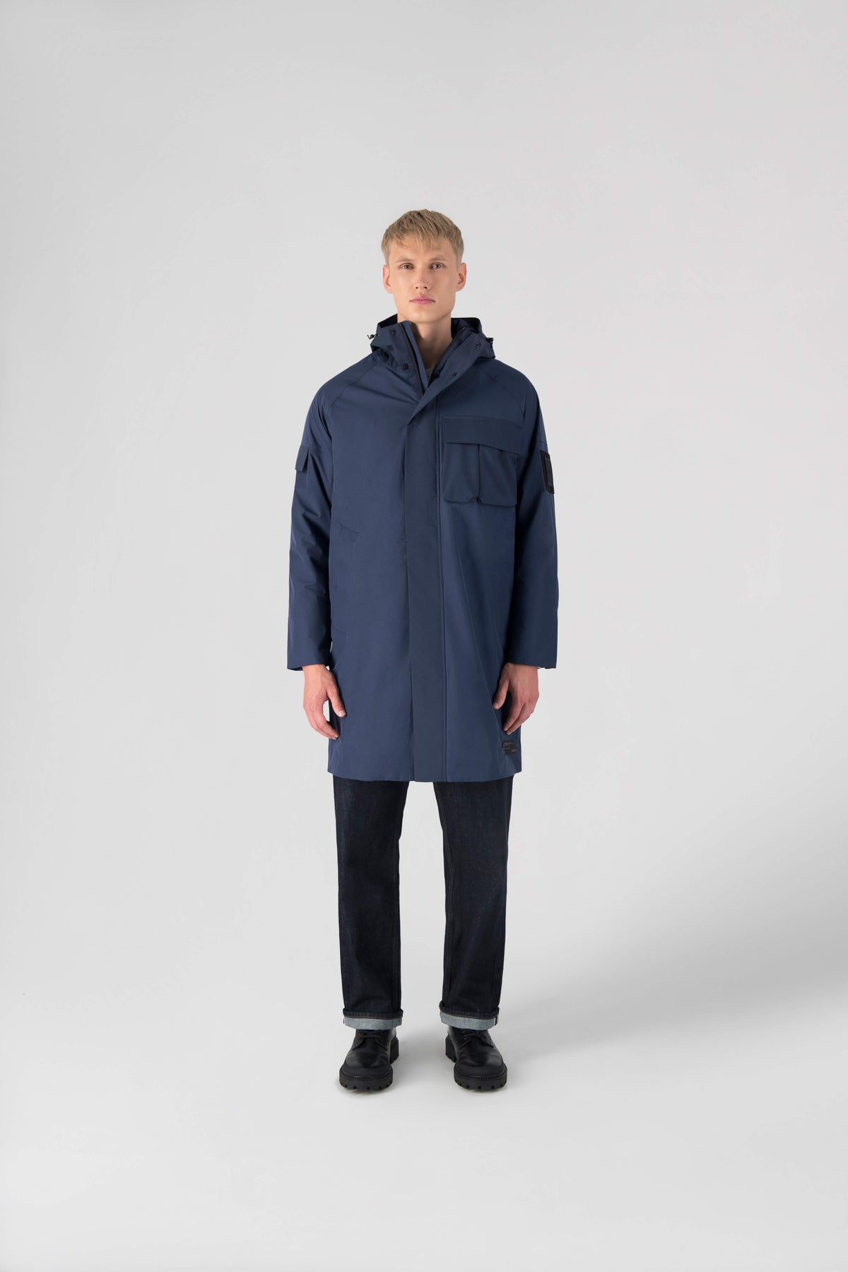 Wylder Men's Performance Rain Jacket in knee length, premium 3-ply Micro Denier and stretch ripstop fabrication, non-removable hood with reflective piping and adjustable draw cord, split utility chest pocket with magnetic flap closure, single welt pockets with magnetic closure at waist, back yoke with mesh ventilation, snap button wind flap, two-way branded zipper at centre front, telescopic sleeves with elasticized cuffs, interior draw cord at waist, in Marine