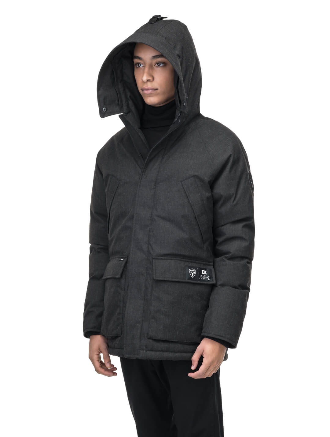 Duncan Keith Heritage Men's Parka in hip length, and features Canadian duck down insulation, non-removable hood with removable coyote fur trim, fleece-lined chest pockets, top and side entry waist pockets, adjustable waist cord, interior zipper pocket, and co-branding with Keith's signature on the left outer waist pocket, in H. Black