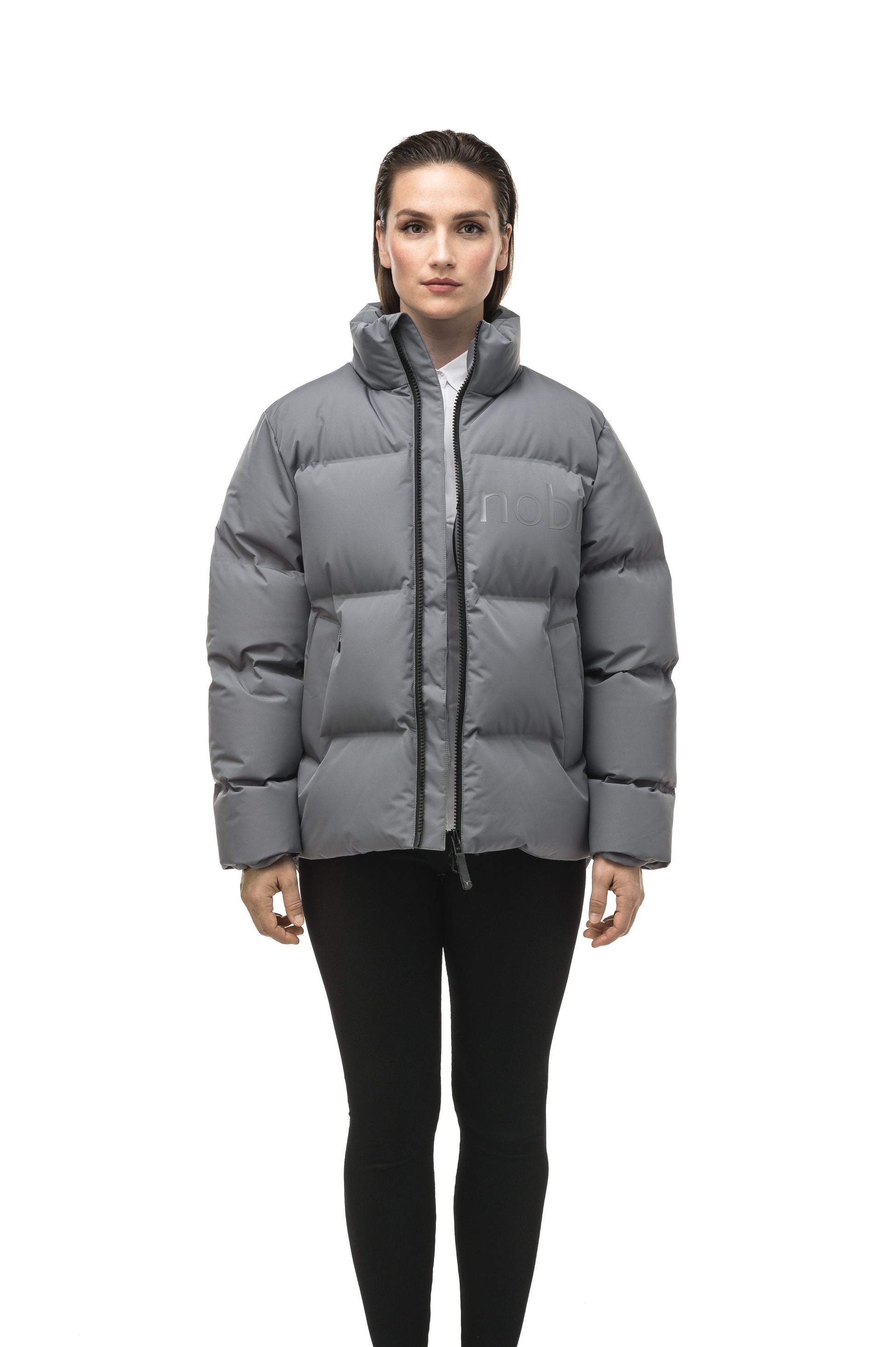 Women's puffer jacket with a minimalist modern design; featuring graphic details like oversized tonal branding, an exposed zipper, and seamless puffer channels to lock in the Premium Canadian Origin White Duck Down in Concrete color